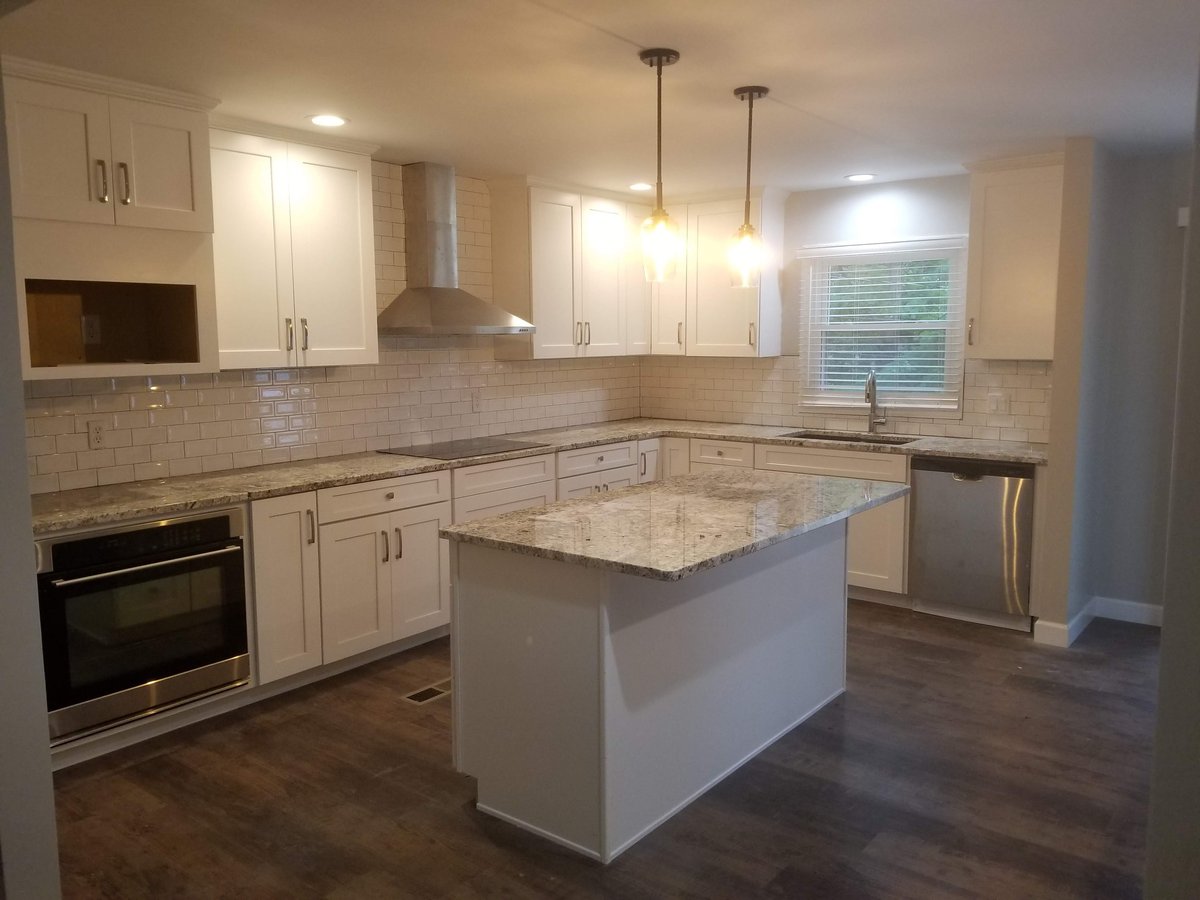 Remodeled kitchen with white cabinets and a granite island